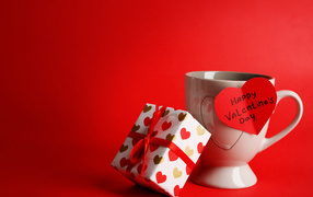 Кружка, сердечко и подарок на красном фоне на День Святого Валентина 