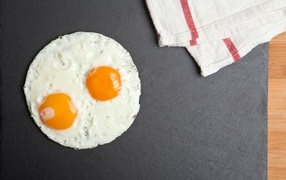 Fried eggs on a gray table with a towel