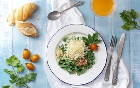 Green noodles with cheese on the table with bread and herbs