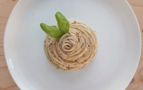 Spaghetti with basil leaves on a white plate
