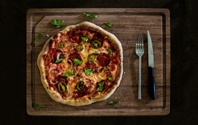 Pizza with cheese and vegetables on a wooden board