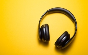 Large black headphones on a yellow background