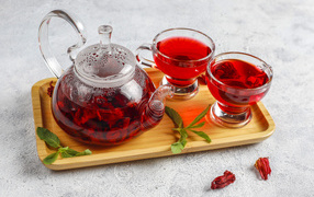 Red tea in a teapot on a tray with cups