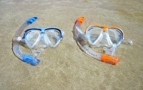 Two masks lie on the wet sea sand