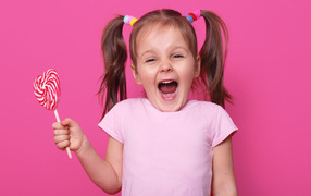 Little girl with lollipop on pink background