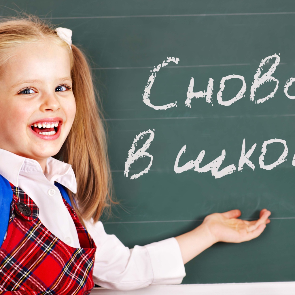 Улыбающаяся маленькая школьница на День знаний 1 сентября у доски
