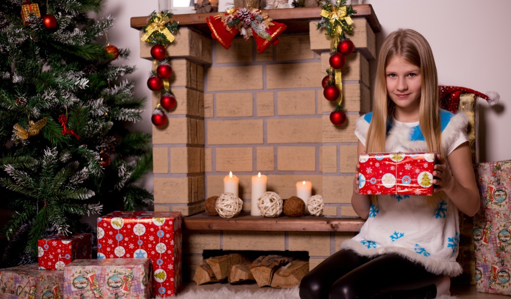 Девочка сидит у камина с подарком на новый год