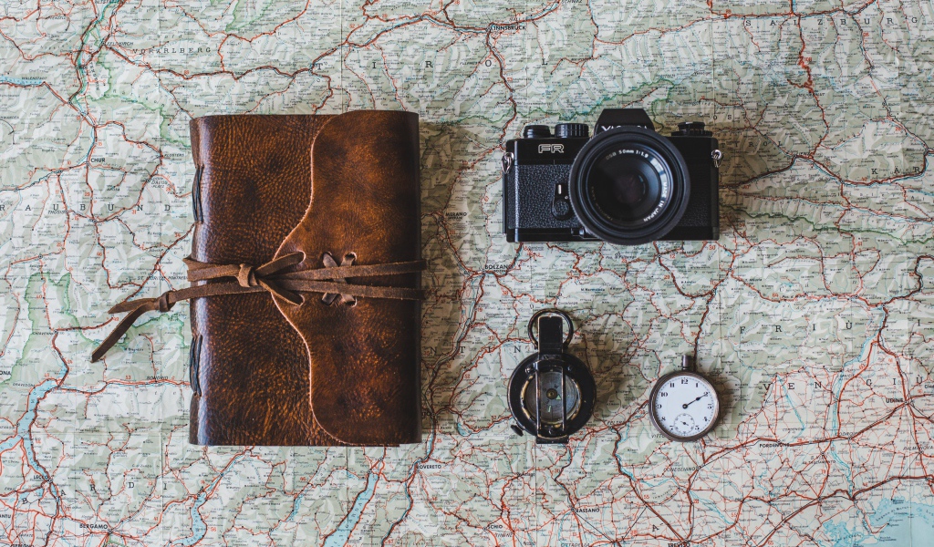 Old camera, compass, clock, notepad and map on the table