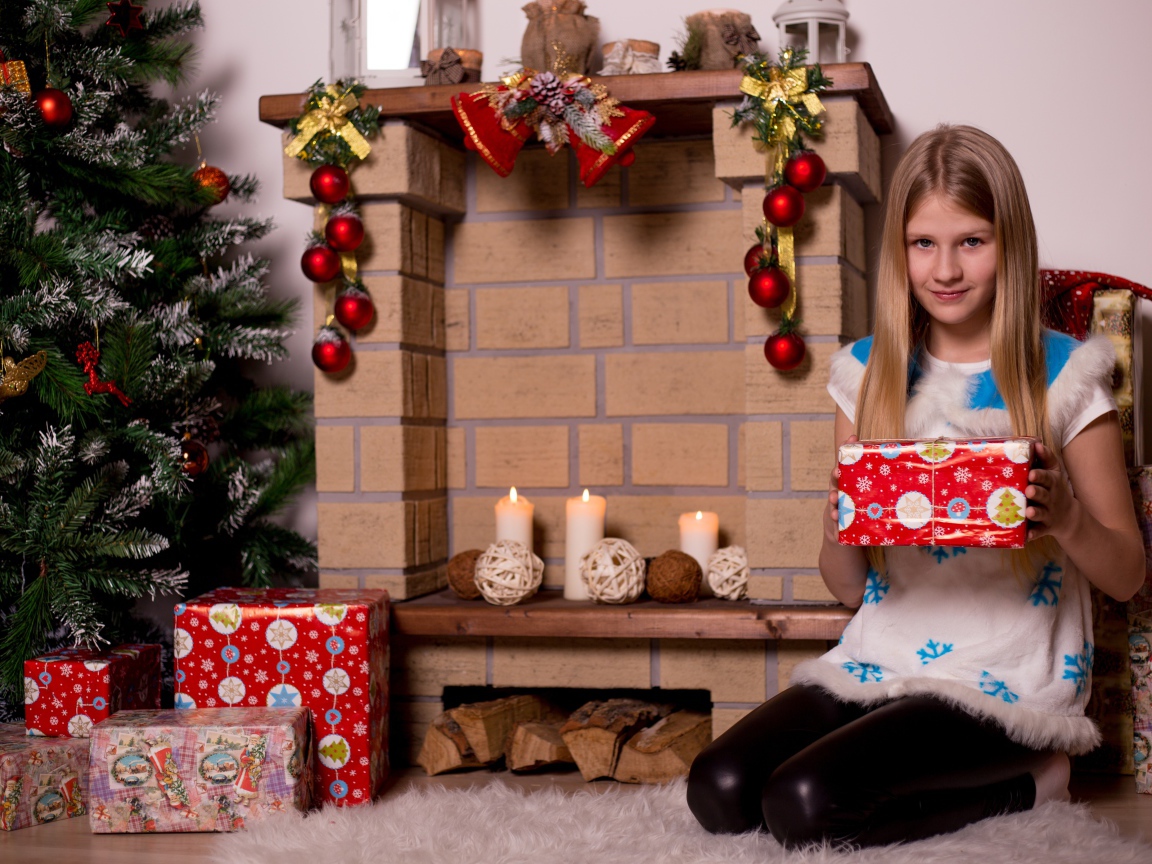 Девочка сидит у камина с подарком на новый год