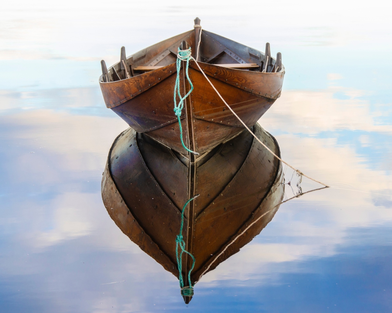 Большая деревянная лодка отражается в воде