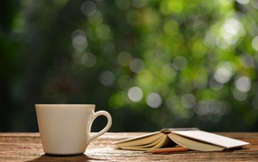White cup on the table with an open book