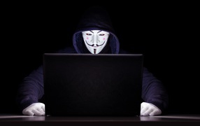 Hacker anonymous masked and hoodie at the laptop