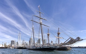 Большая парусная лодка на фоне голубого неба в порту у города