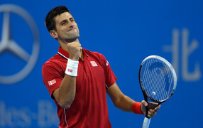 Tennis player Novak Djokovic with a racket rejoices on the court