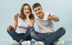 A man and a girl are sitting on the floor against a blue background