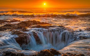 Вода океана стекает в дыру на закате солнца