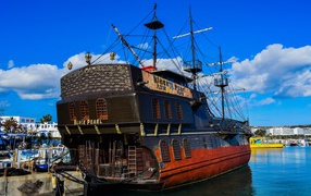 A large black pirate ship stands in the port