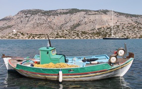 Fishing boat in the water on the background of the mountain