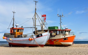 Two fishing boats stand on the sand by the sea