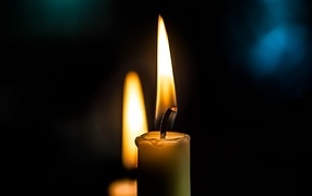 Зажженная свеча на черном фоне