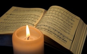 Зажженная свеча с книгой с нотами