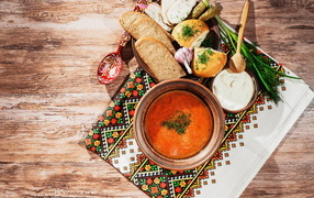 A plate of borscht on the table with lard, bread and herbs