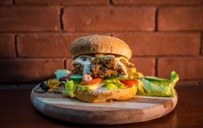 Большой аппетитный гамбургер на фоне стены