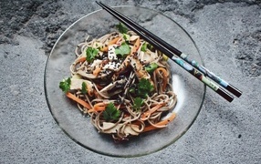Спагетти с мясом и овощами в тарелке с китайскими палочками