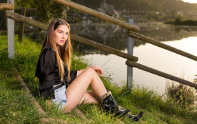 Красивая девушка сидит на берегу реки