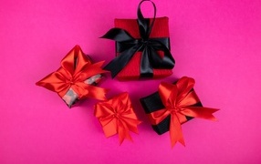 Boxes with gifts and bright bows on a pink background