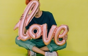 Мужчина держит шарики с надписью любовь