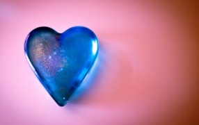 Blue glass heart on a pink table