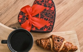Heart-shaped box, coffee and croissant on the table