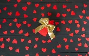 Many small paper hearts with a gift on the table