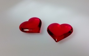 Two red glass hearts on a gray background