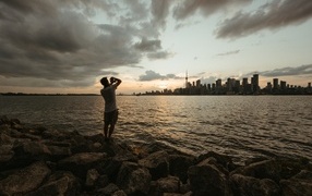 Мужчина делает фото города у моря