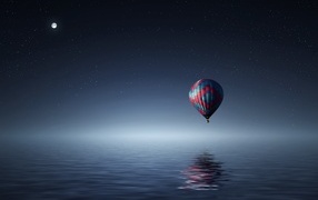 Большой воздушный шар летит над водой ночью
