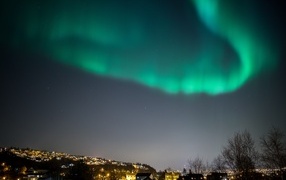 Зеленое полярное сияние в небе над ночным городом