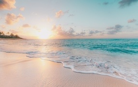 Красивая вода океана на песке в лучах закатного солнца