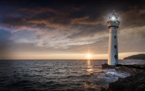 High lighthouse on the seashore at sunset