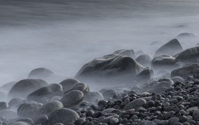Large black stones on the seashore in the fog