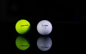 Two golf balls on a black background