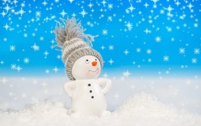 Игрушечный снеговик стоит на белом снегу