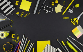 Yellow assorted stationery items on a black surface