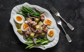 Картофель с мясом, яйцами, спаржей и огурцами на тарелке