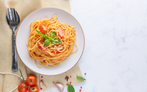 Спагетти с помидорами в тарелке на столе