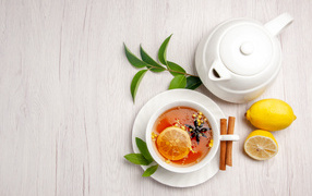 Delicious tea in a white cup on the table with lemon and teapot