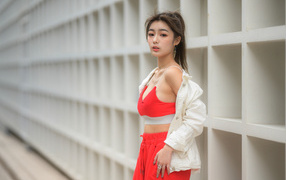 Asian woman in a red tracksuit stands against the wall