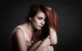 Pensive red-haired girl on a gray background