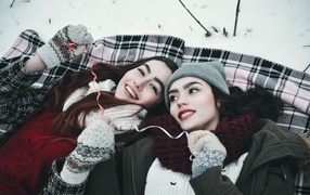 Две красивые молодые девушки лежат на снегу